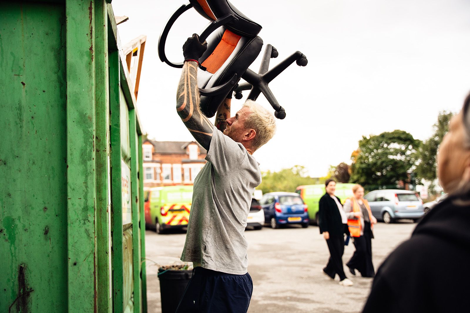 Photo of man throwing old chair into skip